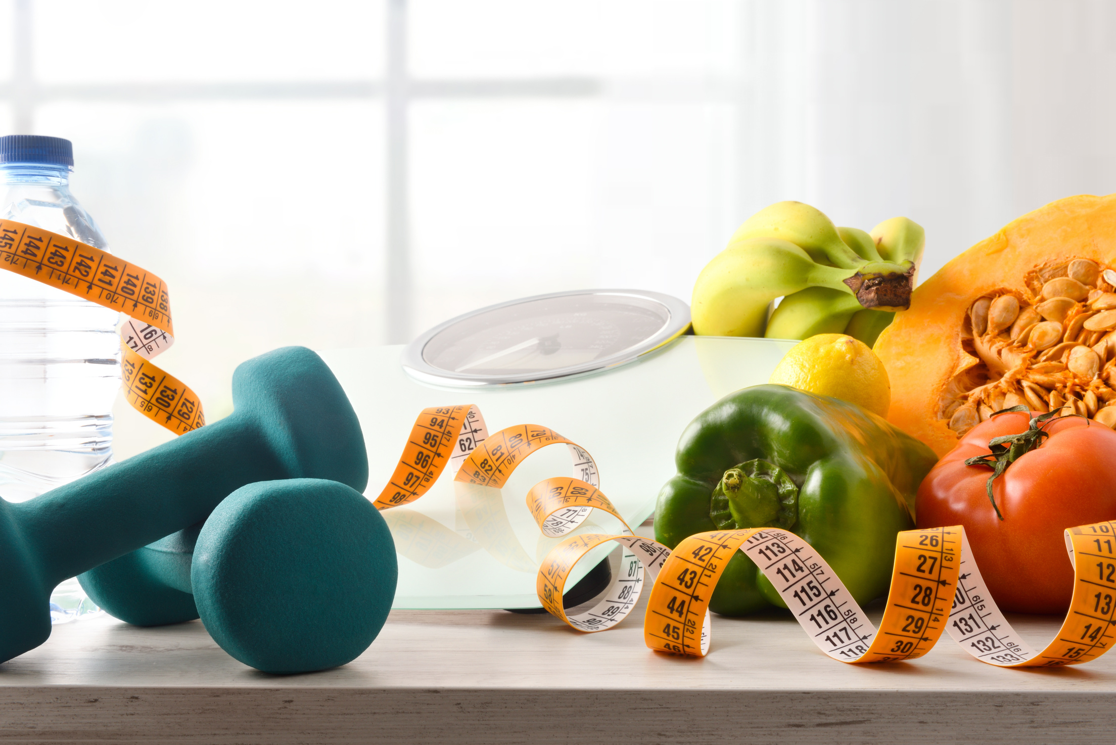 Vegetables dumbbells and scale for healthy life on table front
